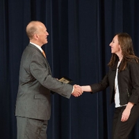 Doctor Potteiger shaking hands with an award recipient in a black blazer and white shirt
